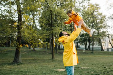 Baba gün batımında mutlu çocuğu parktan kaldırıyor.