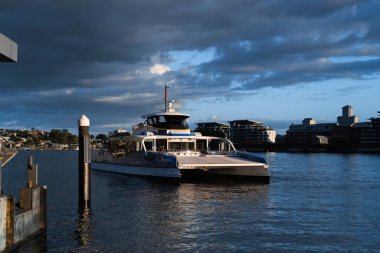 Bir şehir limanında, öğleden sonra gökyüzünün altındaki rıhtıma yaklaşan feribot.
