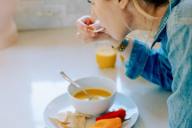Tortilla cipsli tereyağlı kabak çorbası yiyen kadın.
