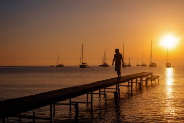 Gün batımında yelkenlilerle iskelede siluet