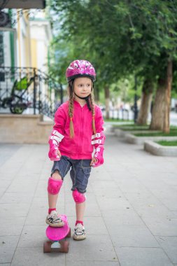 Parkta pembe kaykaylı küçük bir kız..