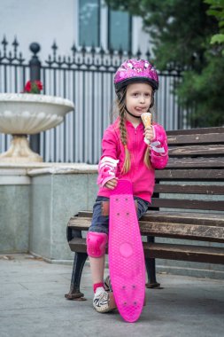 Pembe kaykayıyla bankta oturan dondurmacı kız..