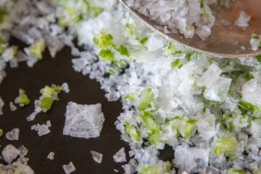 İçine sarımsak parçacıkları karıştırılmış kristal tuz yakın plan.