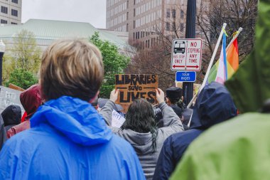 Yüzsüz kalabalık mitingde protesto işaretleri ve bayraklar tutuyor