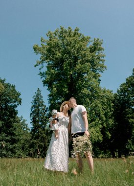 Anne babalar bebek ve çiçekleri tutarken öpüşüyor