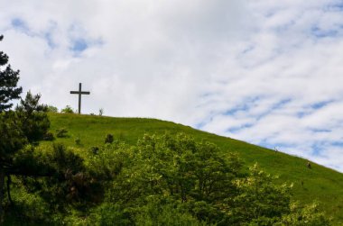 Çapraz ve bulutlu gökyüzü ile yeşil tepe