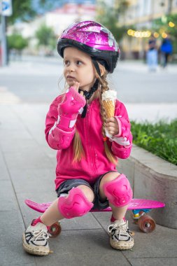 Kasklı küçük kaykaycı şehirde dondurmanın tadını çıkarıyor..
