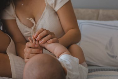 Annenin, erkek bebeğin elini tutarken ki yakın çekimi.