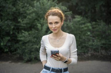 Telefonunu kullanan, gülümseyen ve mesajlaşan bir kadın..