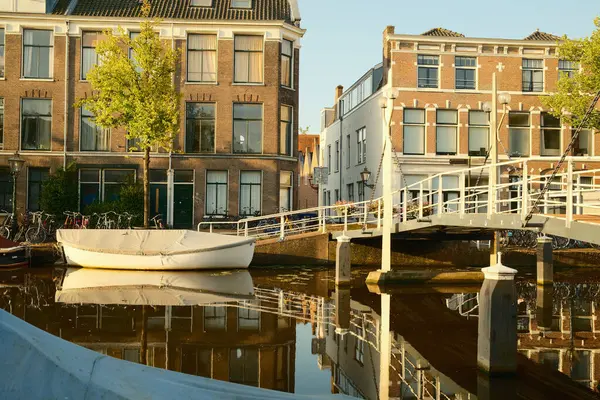 Beyaz kaplı tekne güneş doğarken Hollanda 'nın büyüleyici kasabasında kanala demirlemiş.