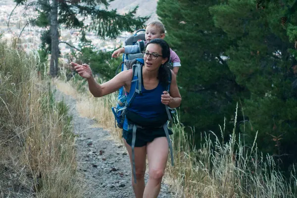 Annesi kasabanın dışında bir patikada yürür. Bebeğini sırtında taşır.