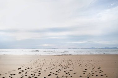 Kumda ayak izleri olan sakin bir sahil manzarası..