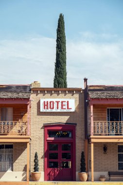 Kırmızı kapı ve selvi ağacının üstündeki otel tabelası tamamen dikey