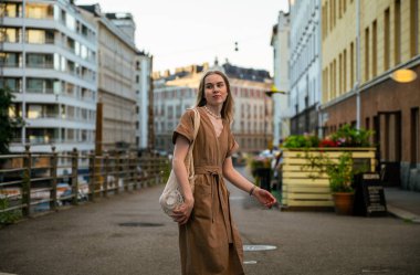 Yaz akşamı elinde ağ çantasıyla karşıdan karşıya geçen genç bir kadın.