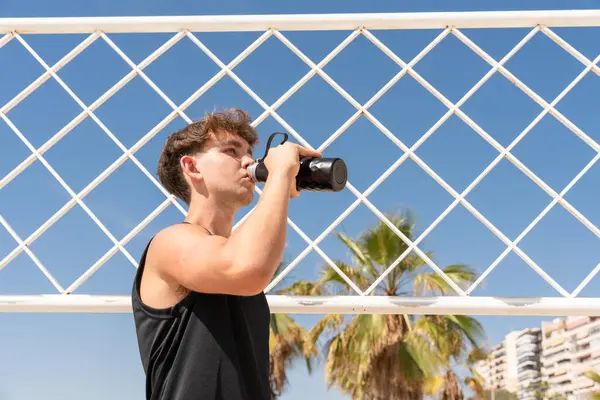 Plaj voleybol sahasında susuz kalan genç bir sporcu.