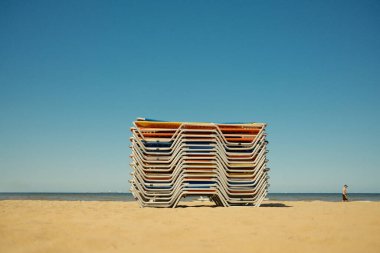 Hollanda 'da güneşli bir sahilde renkli plaj sandalyeleri yığını