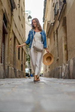 Çekici bir şehirde, kaldırım taşlı bir sokakta yürüyen bir kadın.