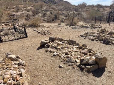 Kaya mezarlıkları ve paslı demir çitlerle ıssız bir çöl mezarlığı.