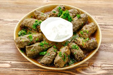 Dolma ekşi krema ve bitkilerle dolu bir tabakta