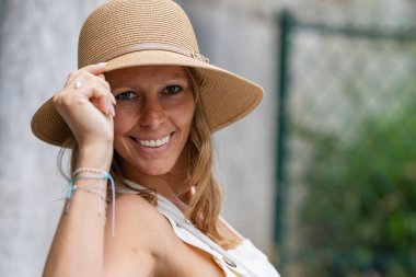 Hasır şapkalı, kendine güvenen, gülümseyen kadın.