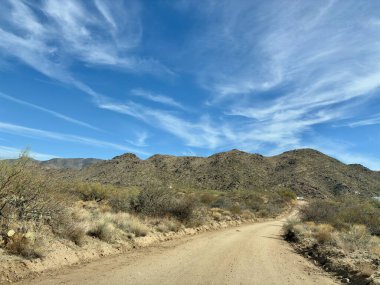 Dağlar ve mavi gökyüzüyle Arizona Çölü 'nden geçen toprak yol.
