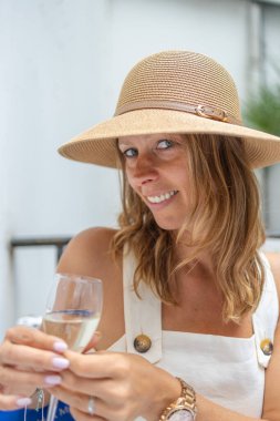 Yazlık şapkalı gülümseyen kadın dışarıda şampanya içiyor..