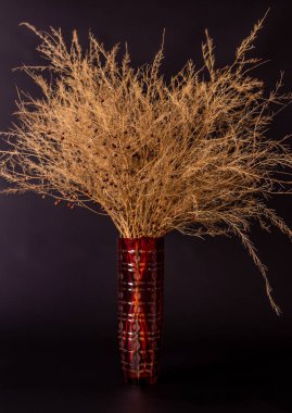 Bir buket kurumuş çiçek uzun bir sığır vazosunda, bir atmosferik...