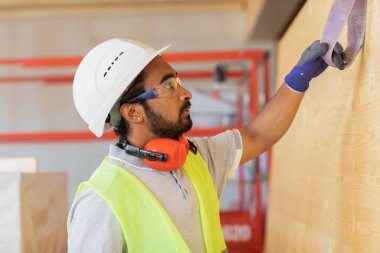 Miğferli ve güvenlik önlüklü işçi işi kontrol ediyor.