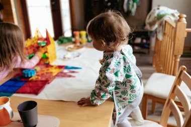 Kız kardeşler evde manyetik fayanslarla oynuyorlar.