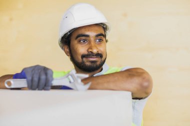 Miğferli ve ceketli bir işçi koridorda duruyor.