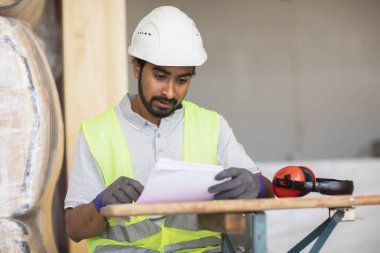 Kask ve güvenlik ceketli işçi bilgileri kontrol ediyor