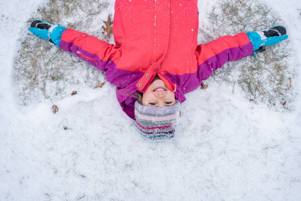 Happy child making snow angel.