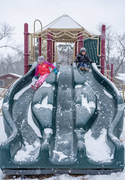 Children Sliding Down a Snow-Covered Slide
