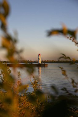 Deniz feneri gün batımında yeşilliklerle çevrili.
