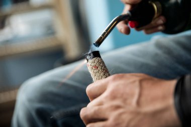 Balıkçı tekne hattını yakmak için meşale kullanıyor.