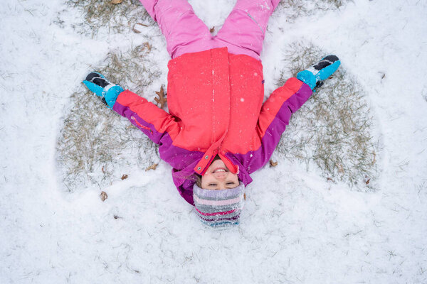 Happy child making a snow angel.
