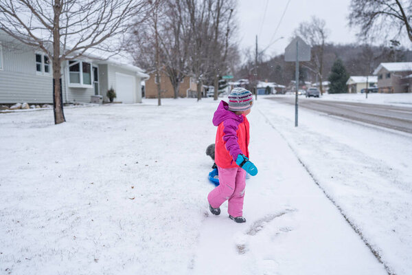 Young girl pulling a sled on a snowy day.