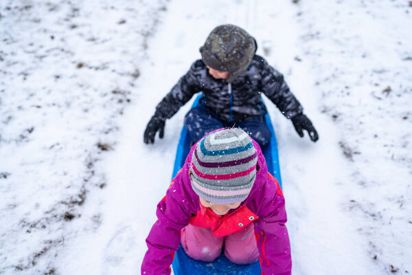 Children getting pulled in sled on a snow day.