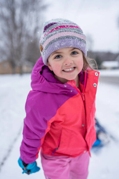 Young girl pulling a sled on a snowy day.