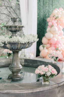 Stone fountain with baby's breath, pink roses, and candles.