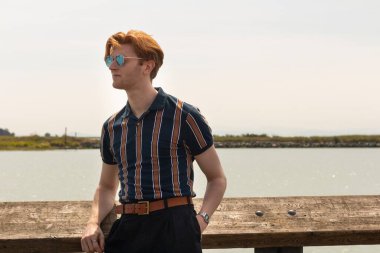 Stylish young man relaxes by the water on a sunny day