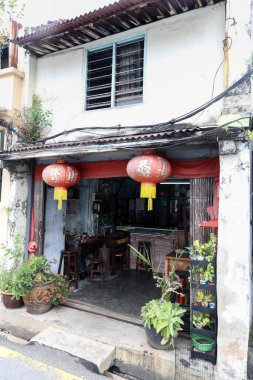 Old red lanterns hanging outside messy peranakan shop