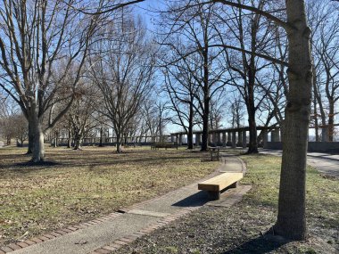 Park scene with trees, benches, pathway, pergola under a clear sky