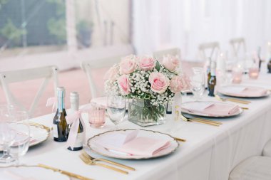 Table set with pink floral centerpiece, gold accents, and champagne.