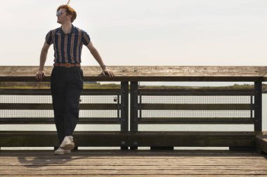 Young man enjoys sunny day on wooden pier with scenic water