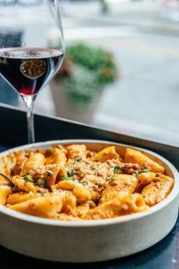 Pencere kenarında kırmızı şarapla servis edilen kırmızı soslu makarna..