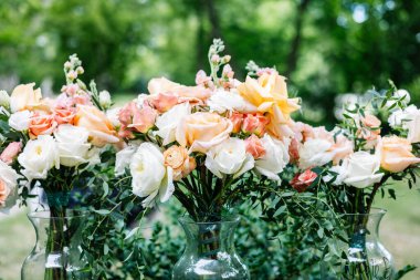 Cam vazolarda zarif şeftali ve beyaz düğün buketlerinin yakın çekimi..