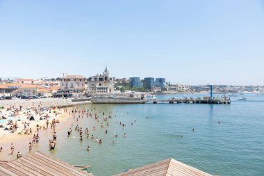Kalabalık yaz plajı ve güneşli Cascais, Portekiz liman manzarası