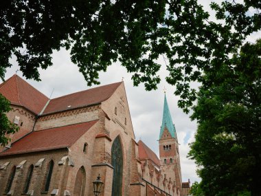Augsburg cathedral rising majestically behind lush green trees
