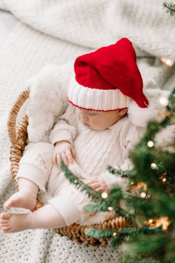 Noel Baba şapkalı uyuyan bebek Noel ağacının altında..